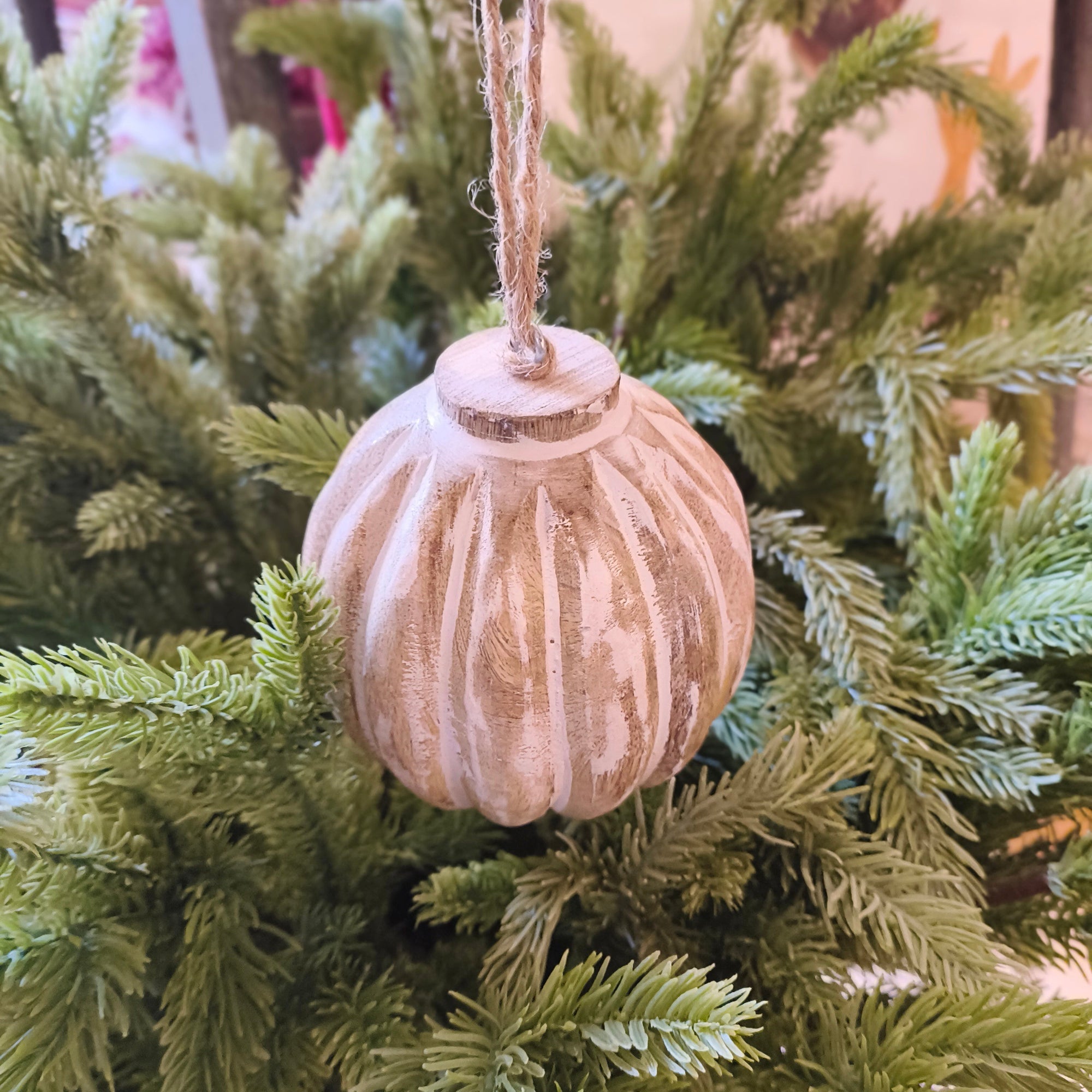 large wooden bauble with twine hanging on a Christmas tree