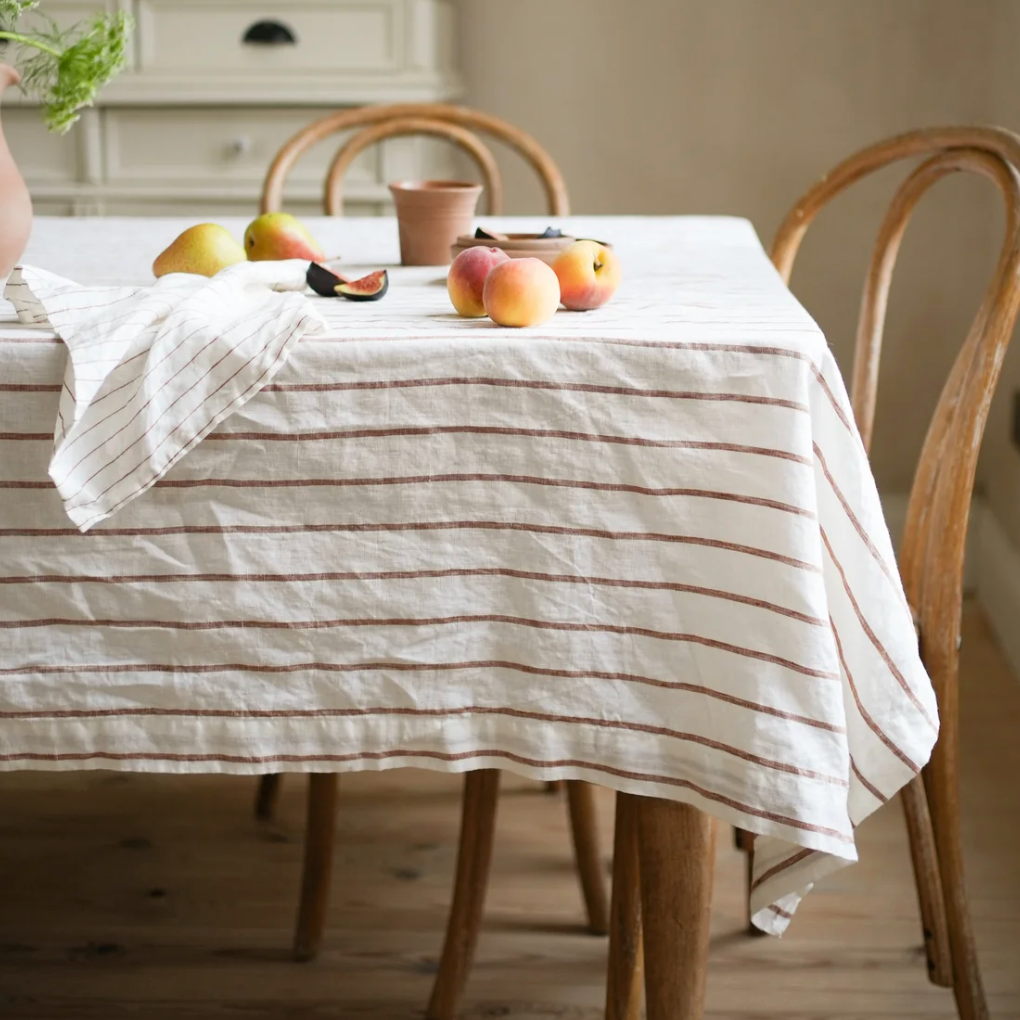 Dining table with striped tablecloth and apples on a wooden floor