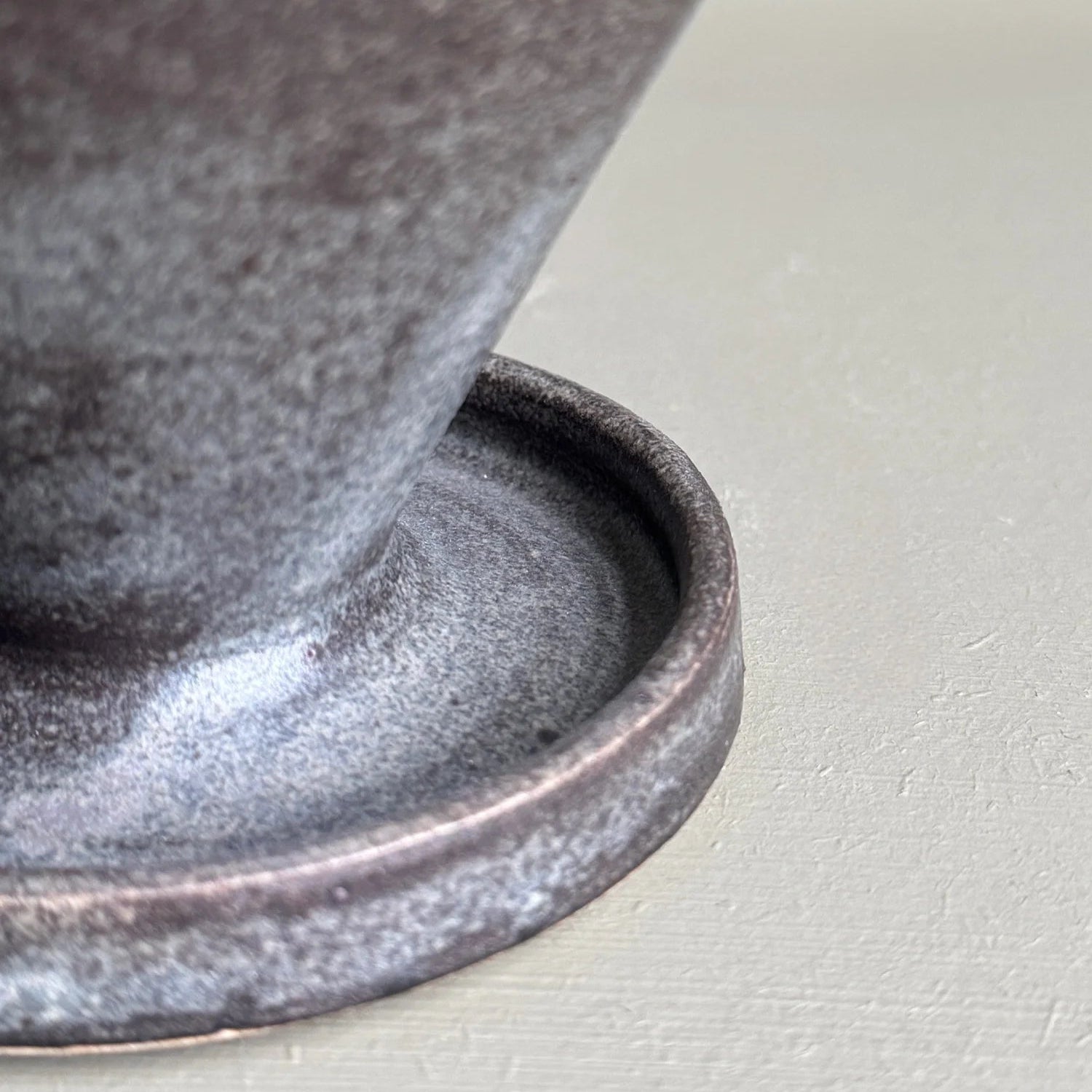 Close-up of a textured ceramic pot on a light gray background