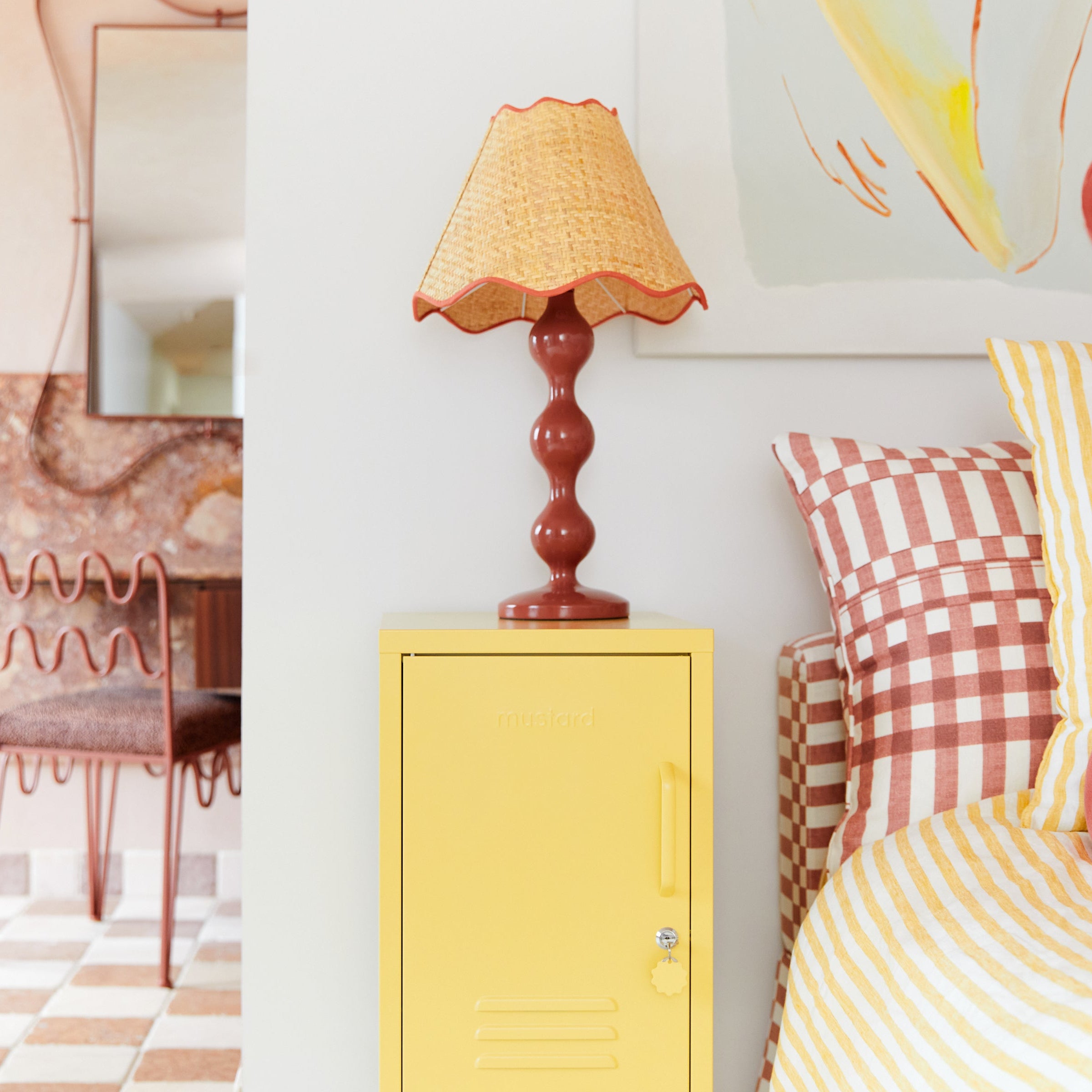 Yellow locker with a lamp on top, checkered pillows, and a patterned chair in a room.