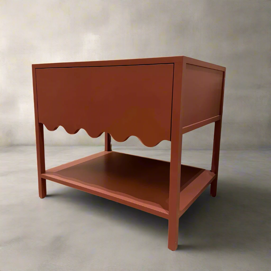 A red bedside table with a scalloped edge design and a lower shelf, made of wood, with a soft.runner drawer.