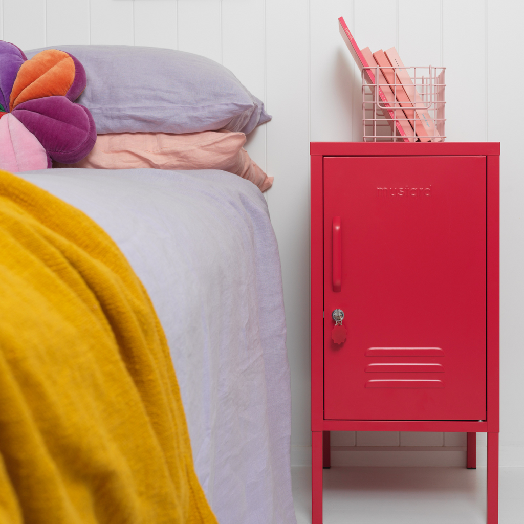 Red locker-style cabinet next to a bed with colorful bedding