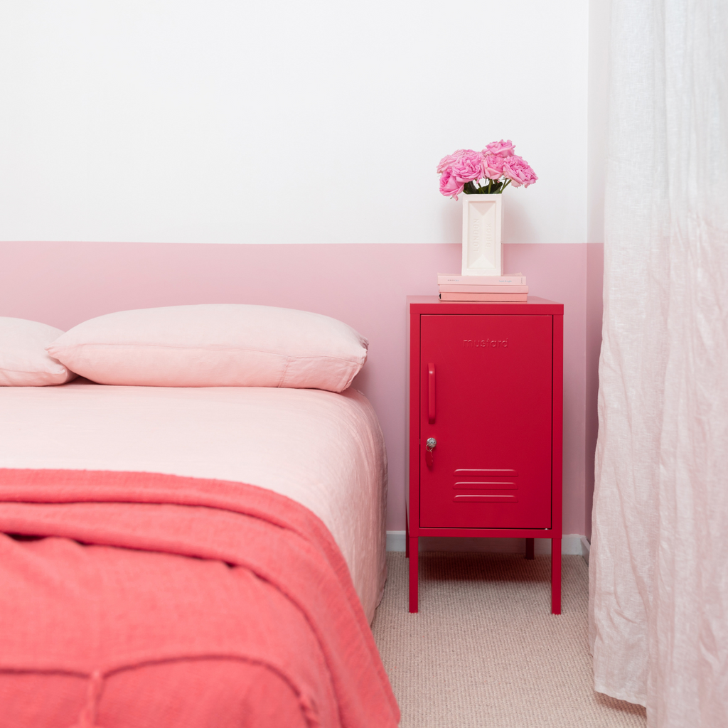 Pink bedroom with a red locker, pink bedspread, and pink flowers.