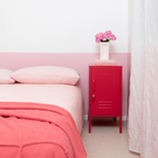 Pink bedroom with a red locker, pink bedspread, and pink flowers.