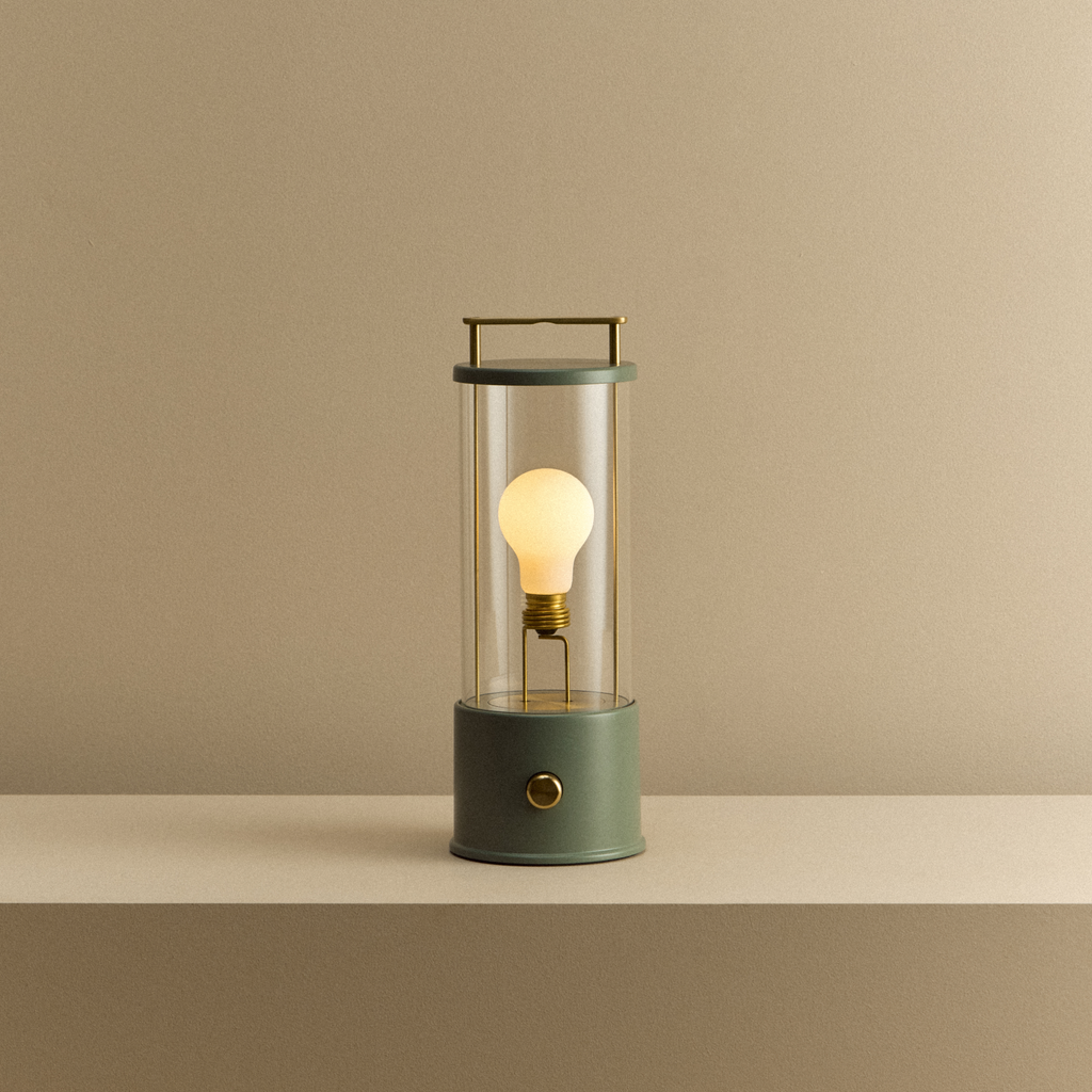 Green lantern-style lamp with a lit bulb on a beige surface and background