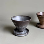 Two ceramic cups on a light gray surface with a neutral background