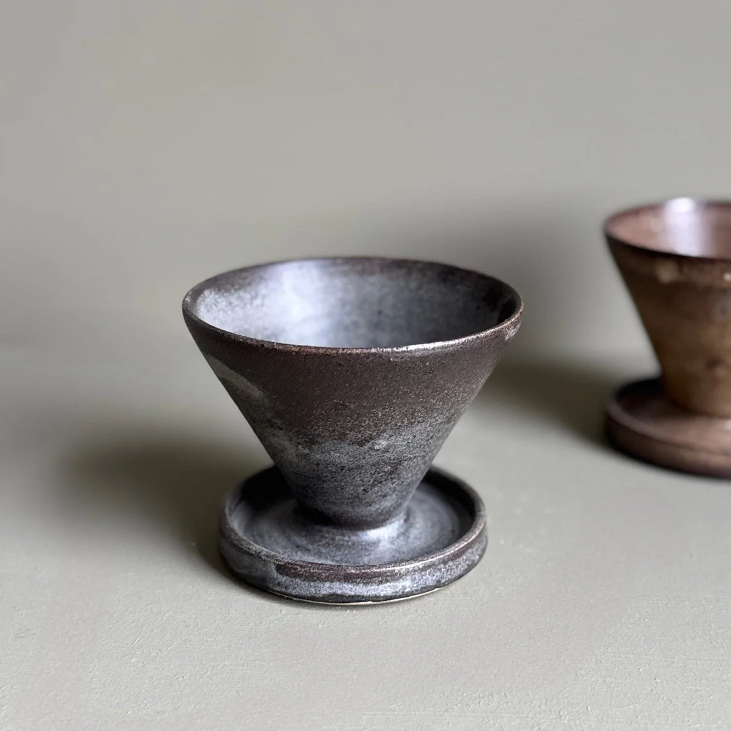 Two ceramic cups on a light gray surface with a neutral background