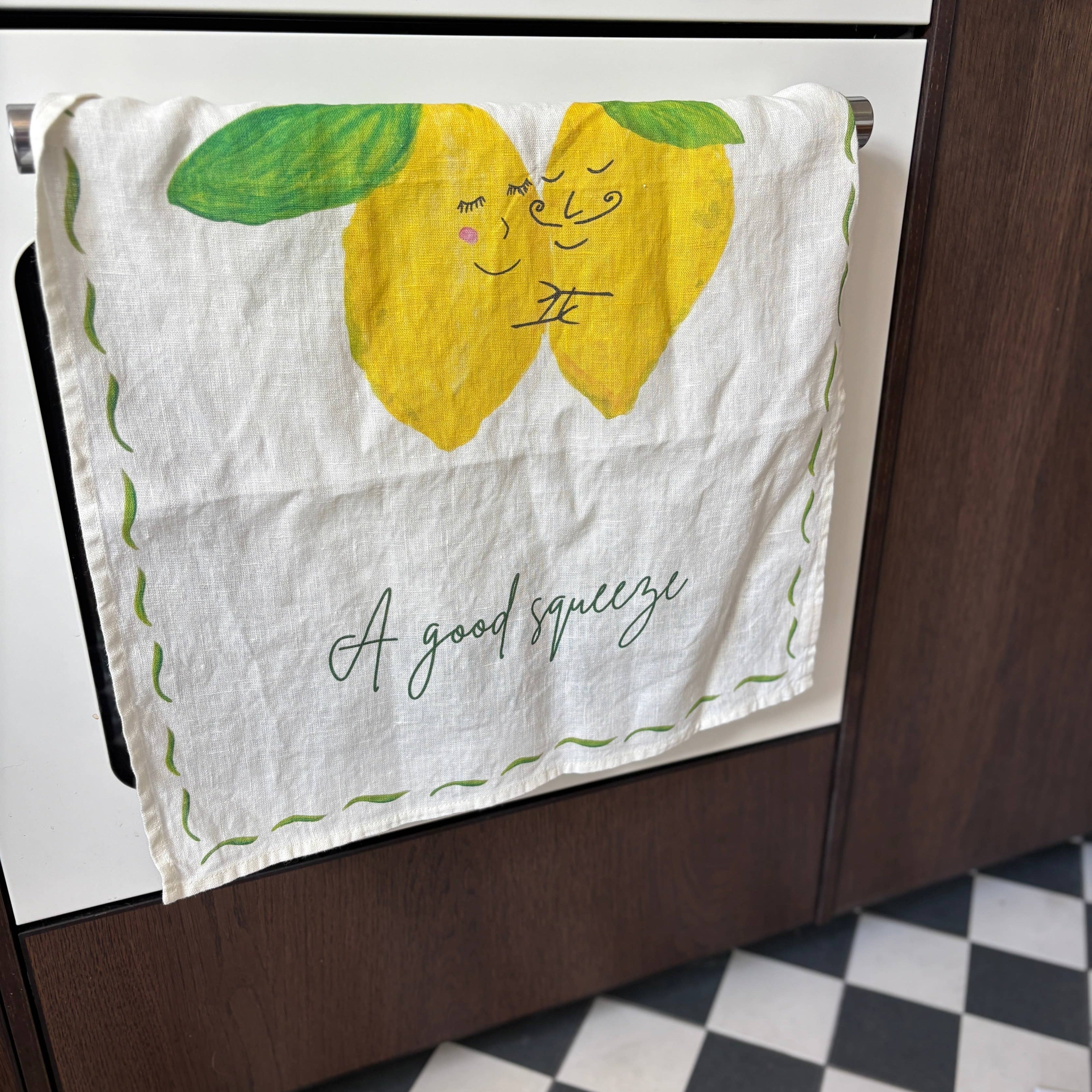 Kitchen towel with lemon design hanging on a stove.