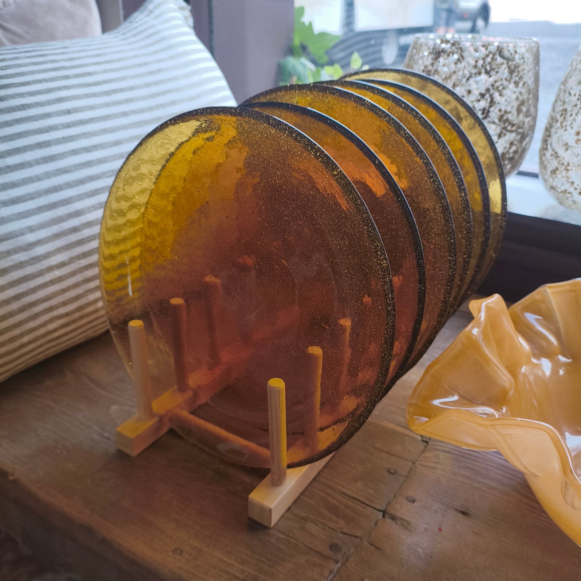 Set of amber glass plates on a wooden stand with a blurred background