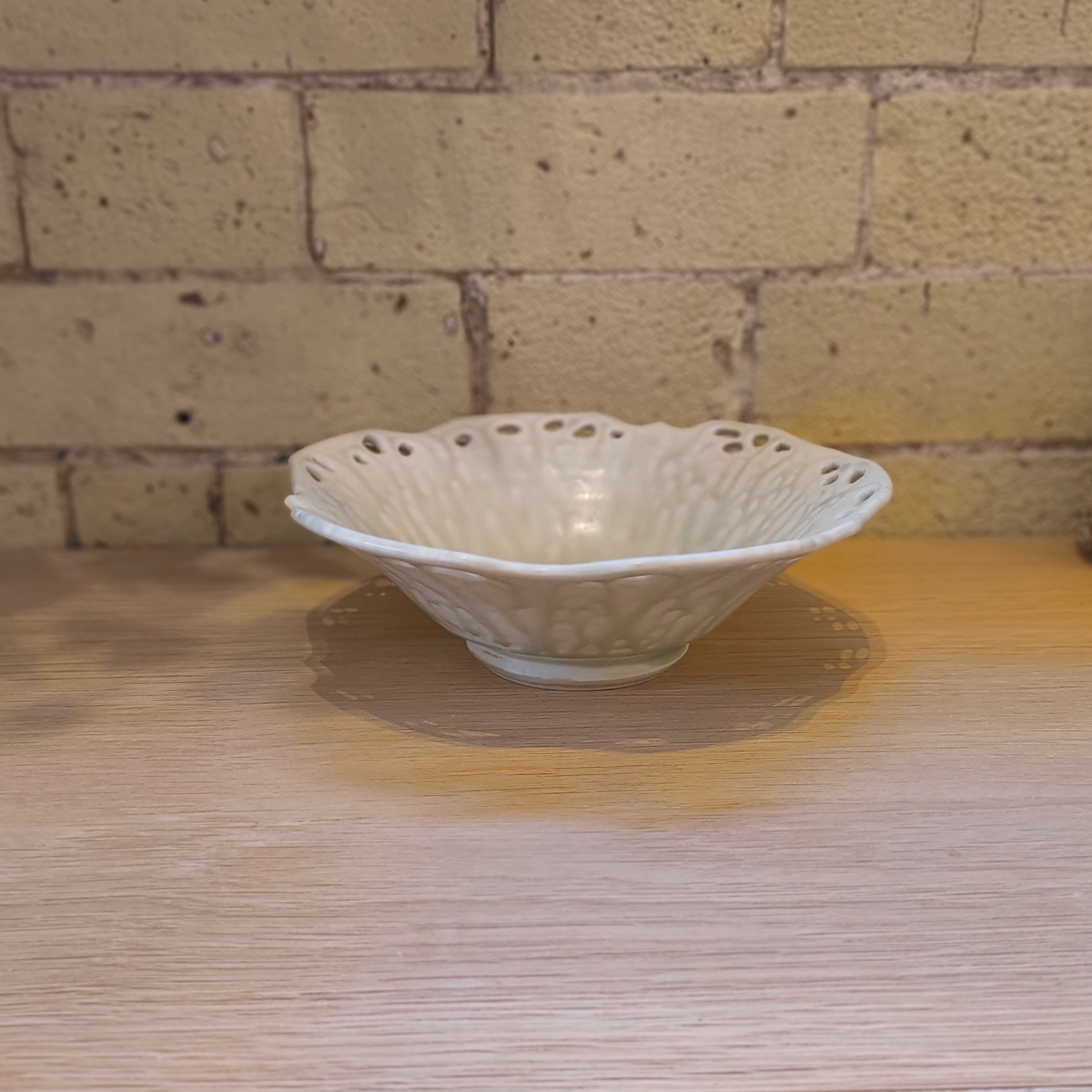 Sakashi ceramic bowl on a wooden table with brick wall behind