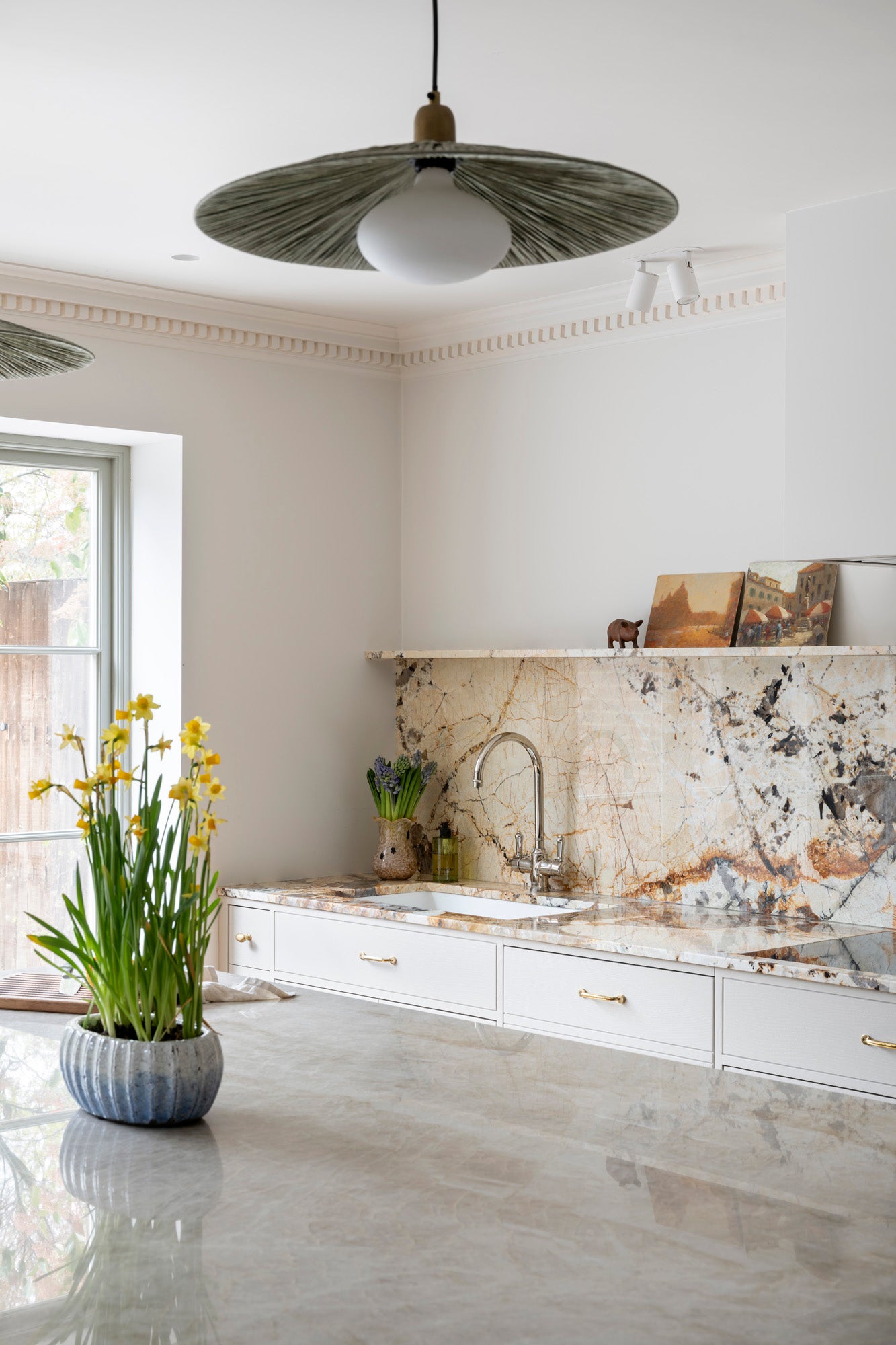Modern interior designed kitchen with marble countertop, backsplash, and pendant light.