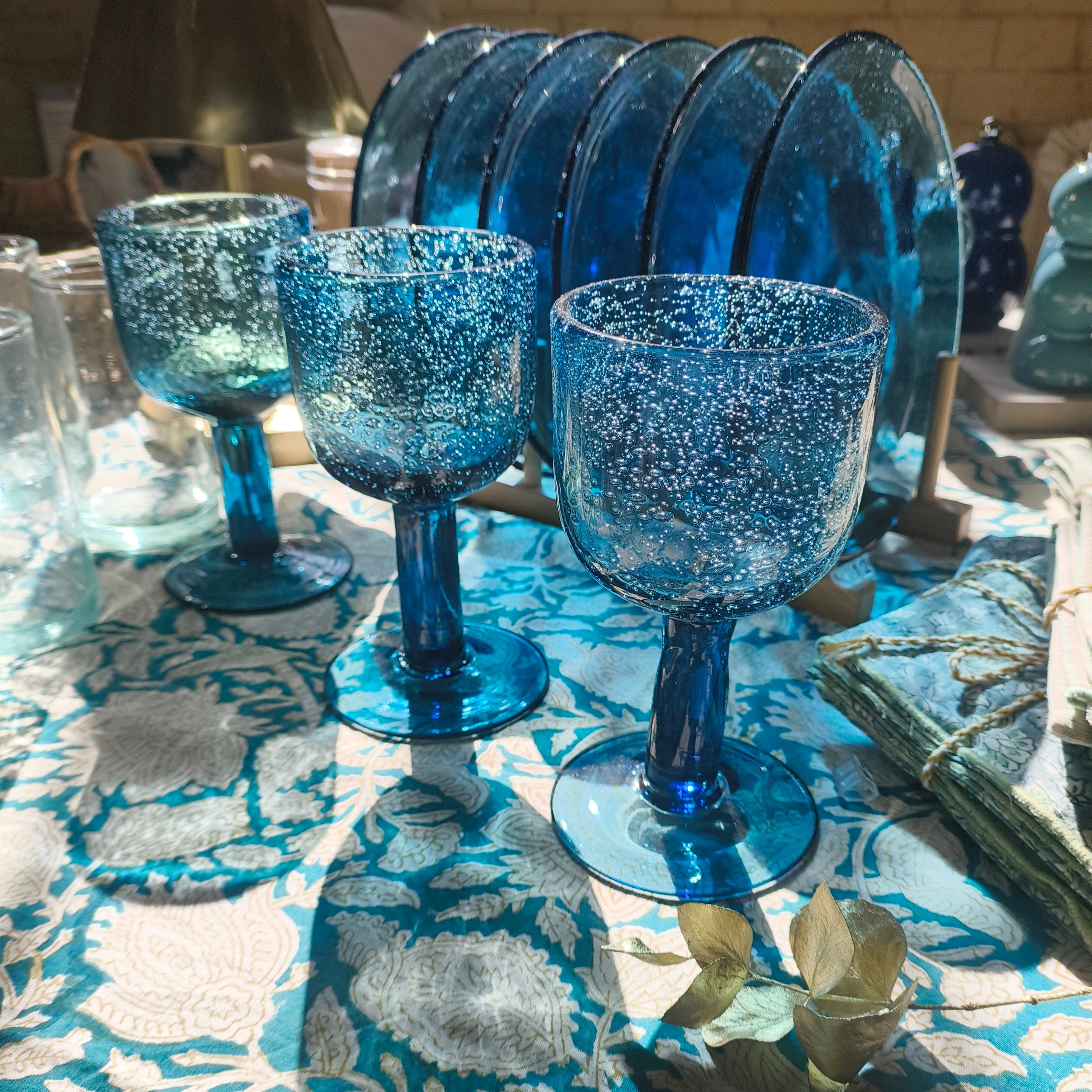 Set of blue glass goblets on a patterned tablecloth