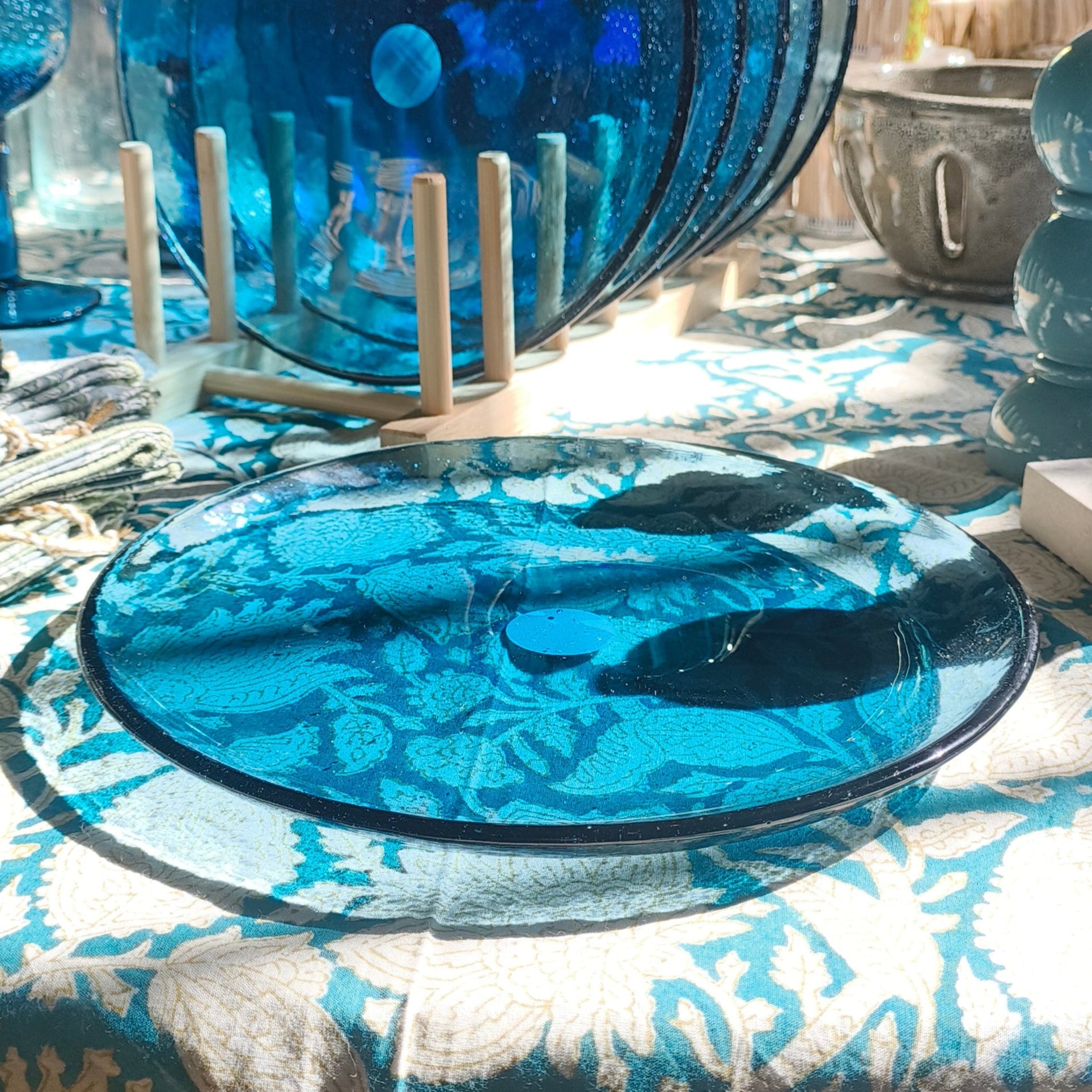 Blue glassware on a patterned tablecloth with a blurred background