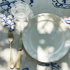 White ceramic plate with a fork on a blue and white patterned tablecloth