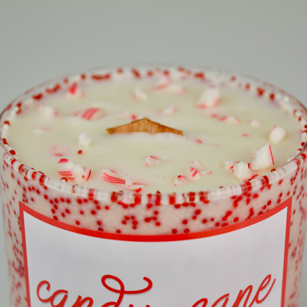 Candle with peppermint candy cane design on a gray background