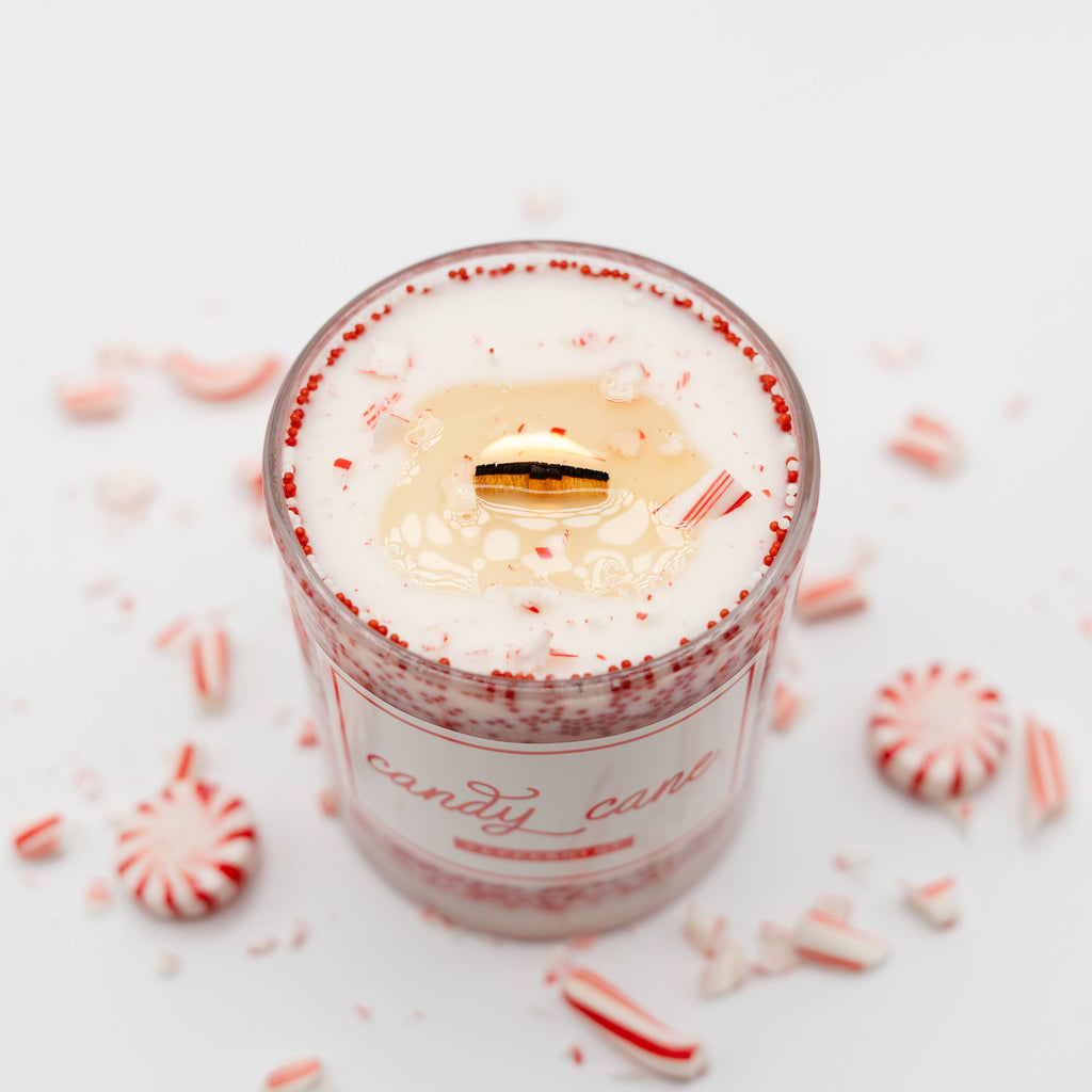 Candle in a glass jar with peppermint candy on a white background