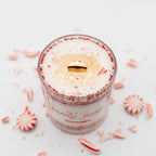 Candle in a glass jar with peppermint candy on a white background