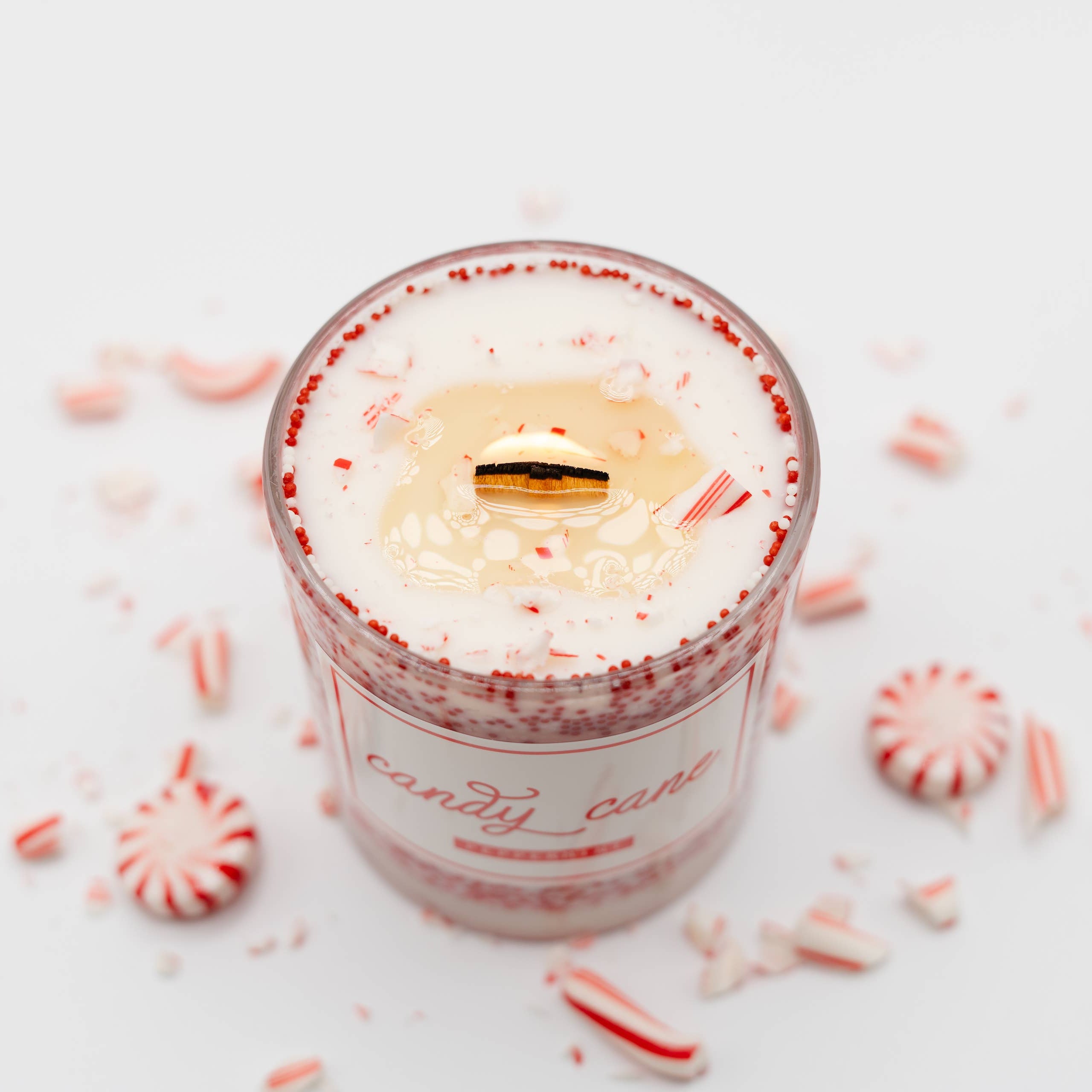 Candle in a glass jar with peppermint candy on a white background