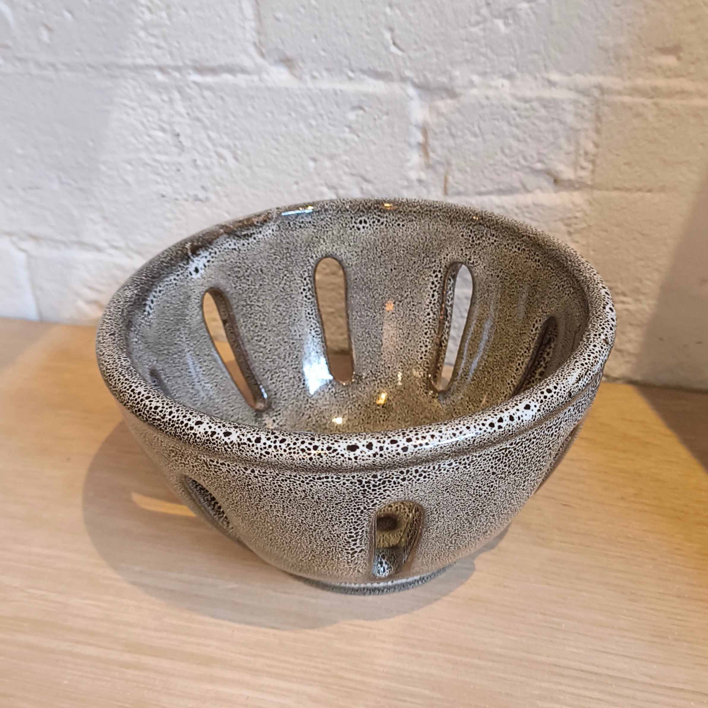 Ceramic bowl with textured surface on a wooden surface with a white brick wall background