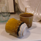 Two ceramic mugs with decorative patterns on a white surface.