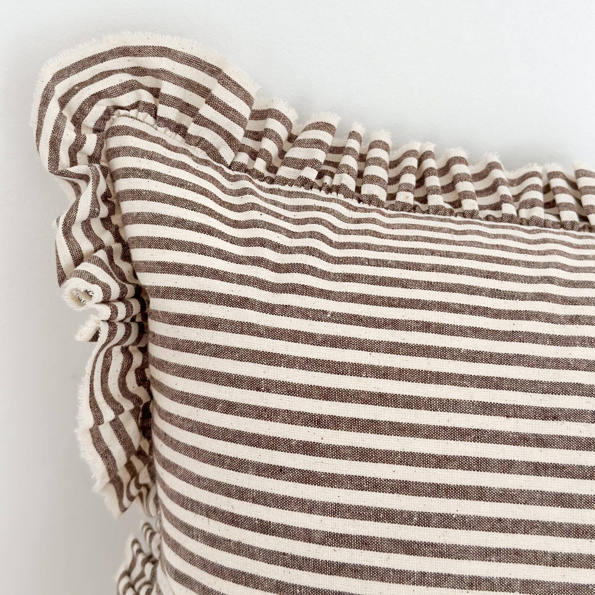 Close-up of a striped pillow with ruffled edge on a light background