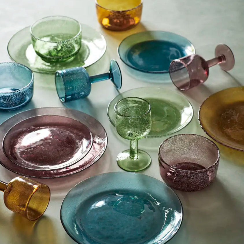 Set of colorful glass plates and glasses on a light surface