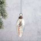 Decorative Christmas ornament hanging on a white background with a branch in the corner.