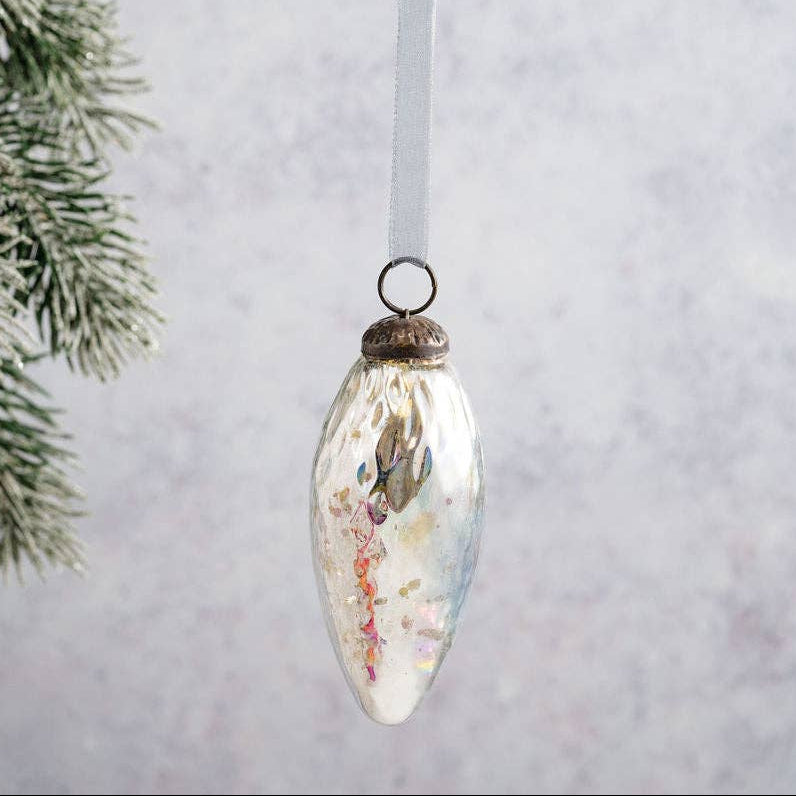 Decorative Christmas ornament hanging on a white background with a branch in the corner.