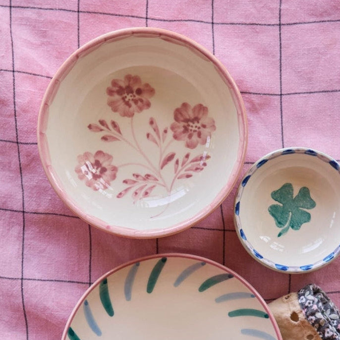 Decorative ceramic plates with floral designs and a spoon on a pink checkered background