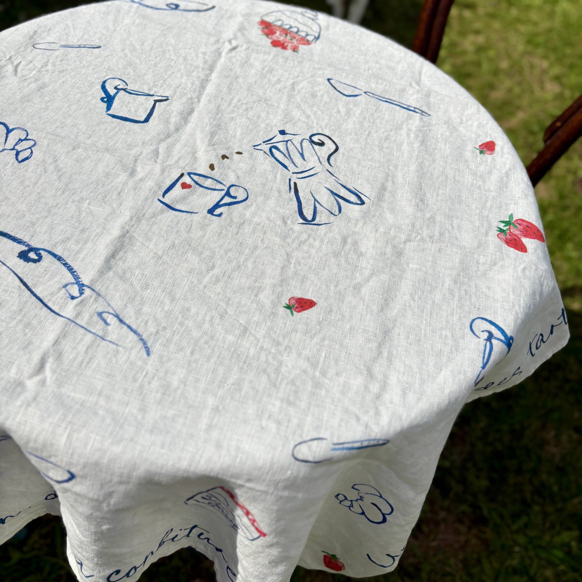 White table cloth with blue and red designs on a grassy background