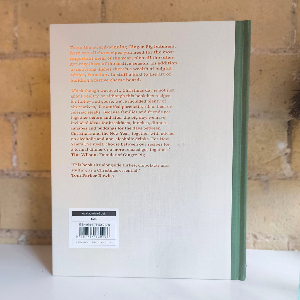 Book with a green spine on a white surface against a brick wall background