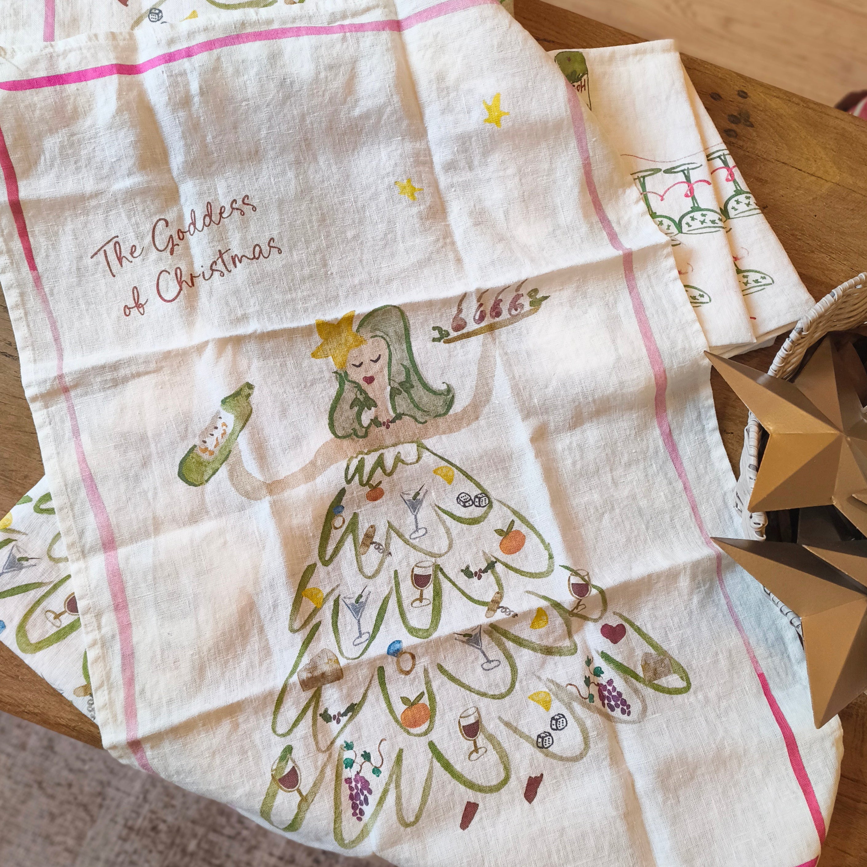 Decorative kitchen towels with Christmas-themed designs on a wooden surface.