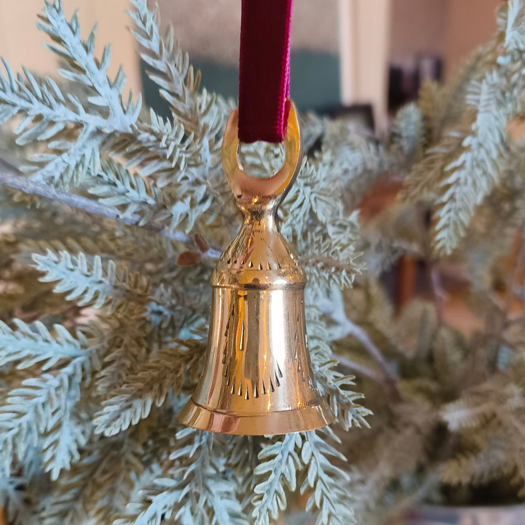 Gold bell ornament on a branch with a blurred background