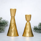 Two gold candle holders on a white background with greenery.