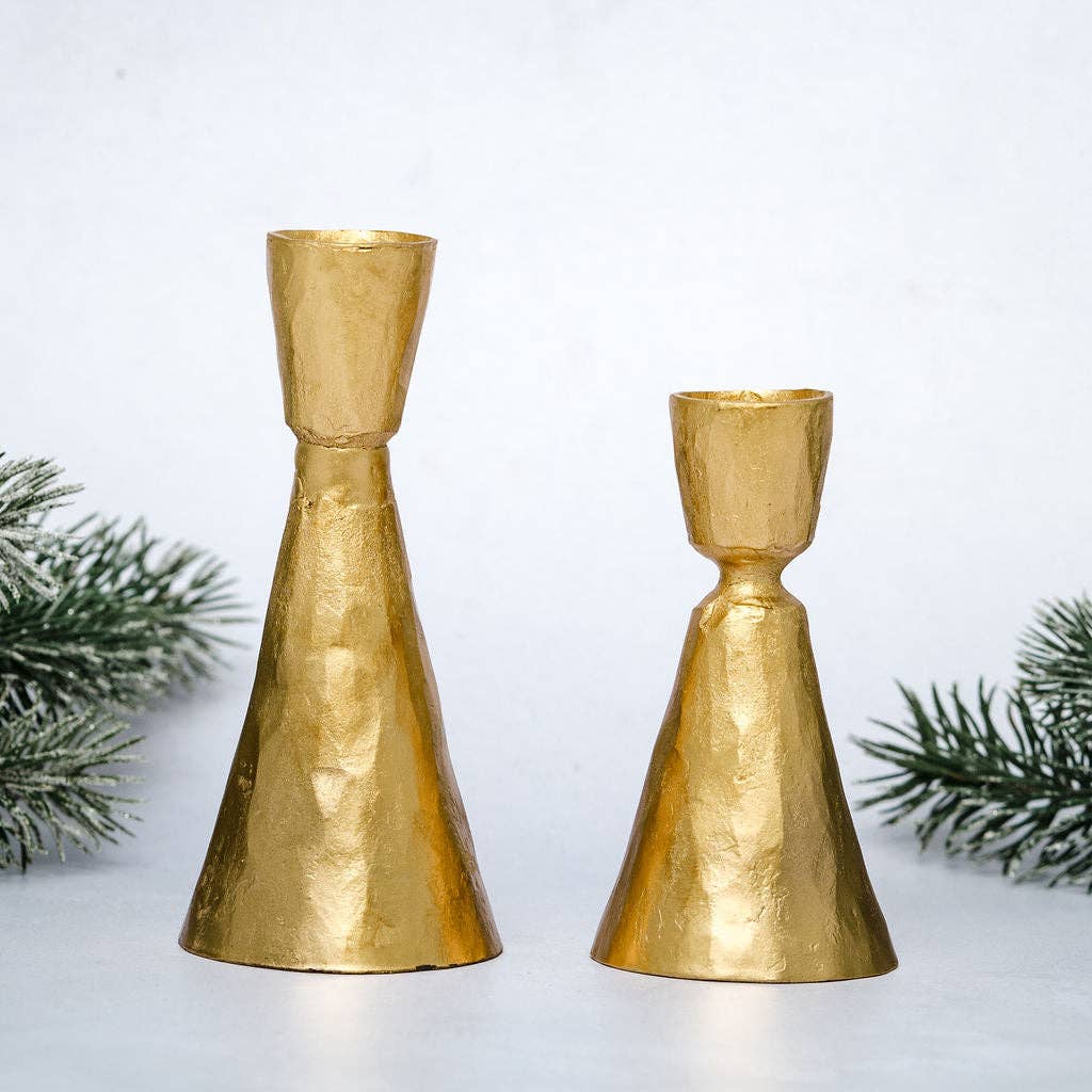 Two gold candle holders on a white background with greenery.