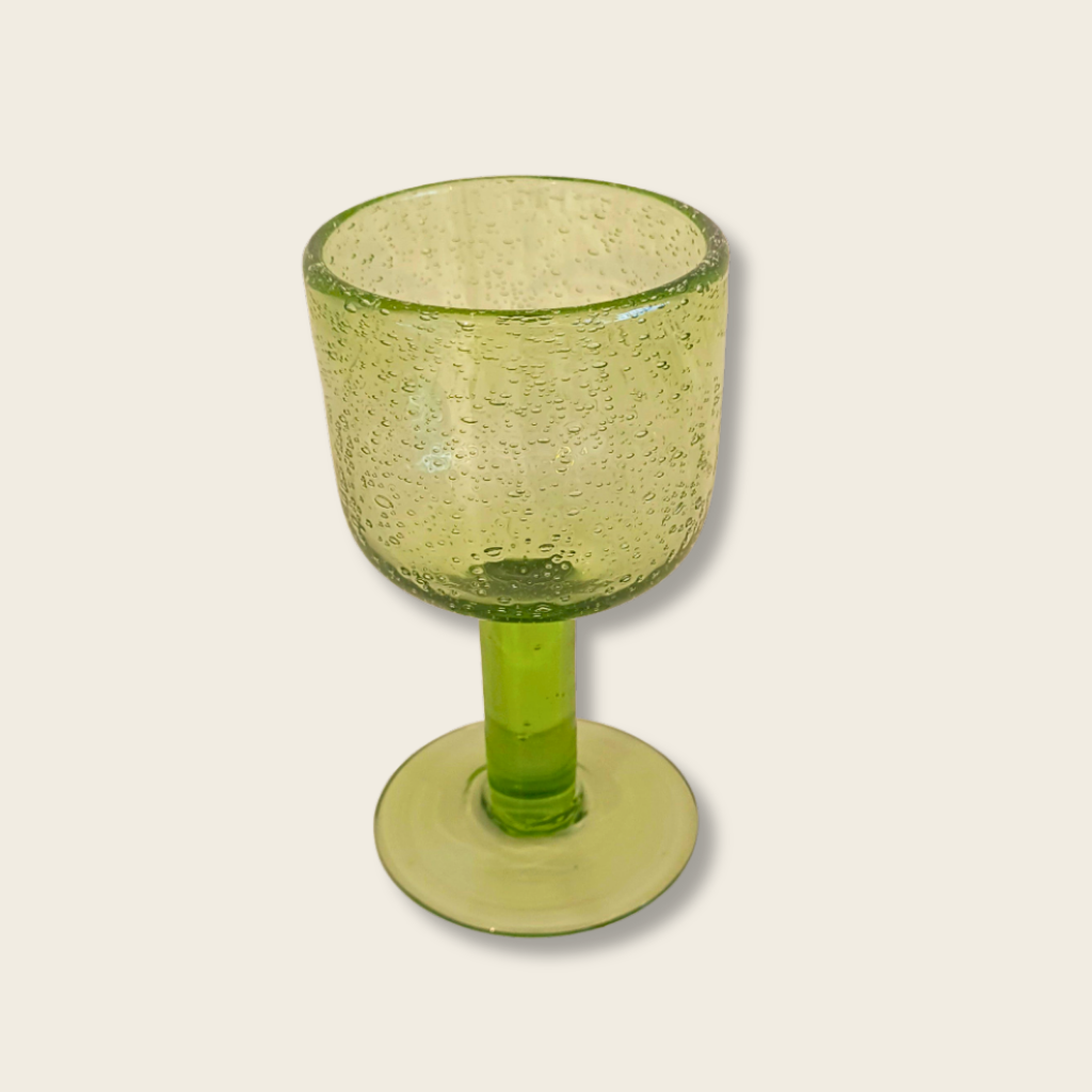 Green glass goblet with a beige background