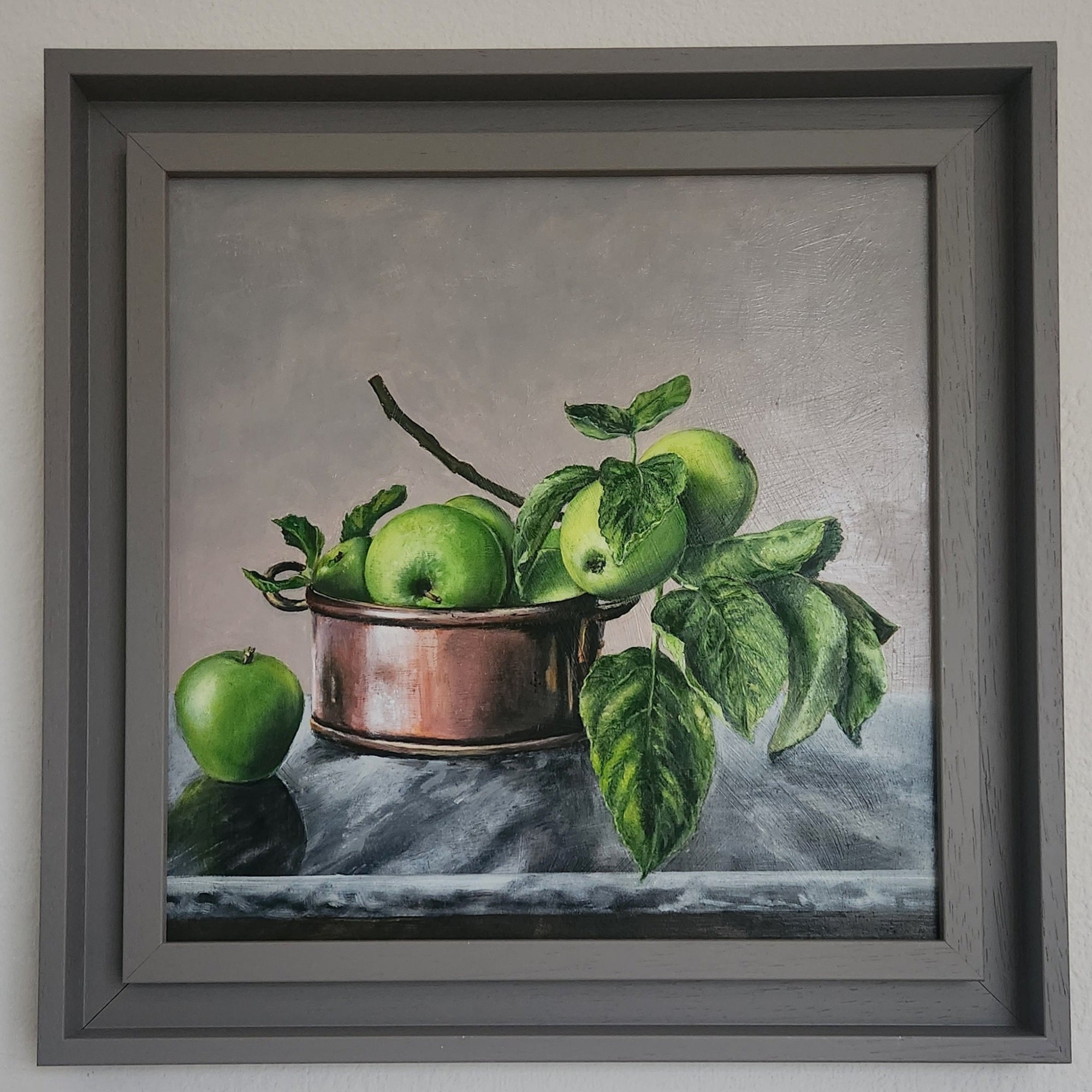 Framed artwork of green apples in a copper bowl on a gray background