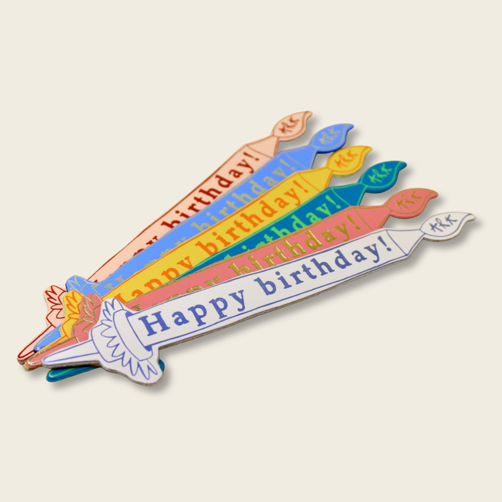 Colorful birthday candle-shaped card with 'Happy birthday!' text on a beige background