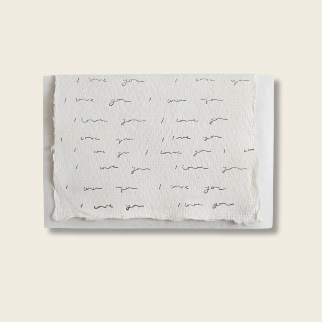 Handmade cotton rag paper card with i love you repeated on a beige background