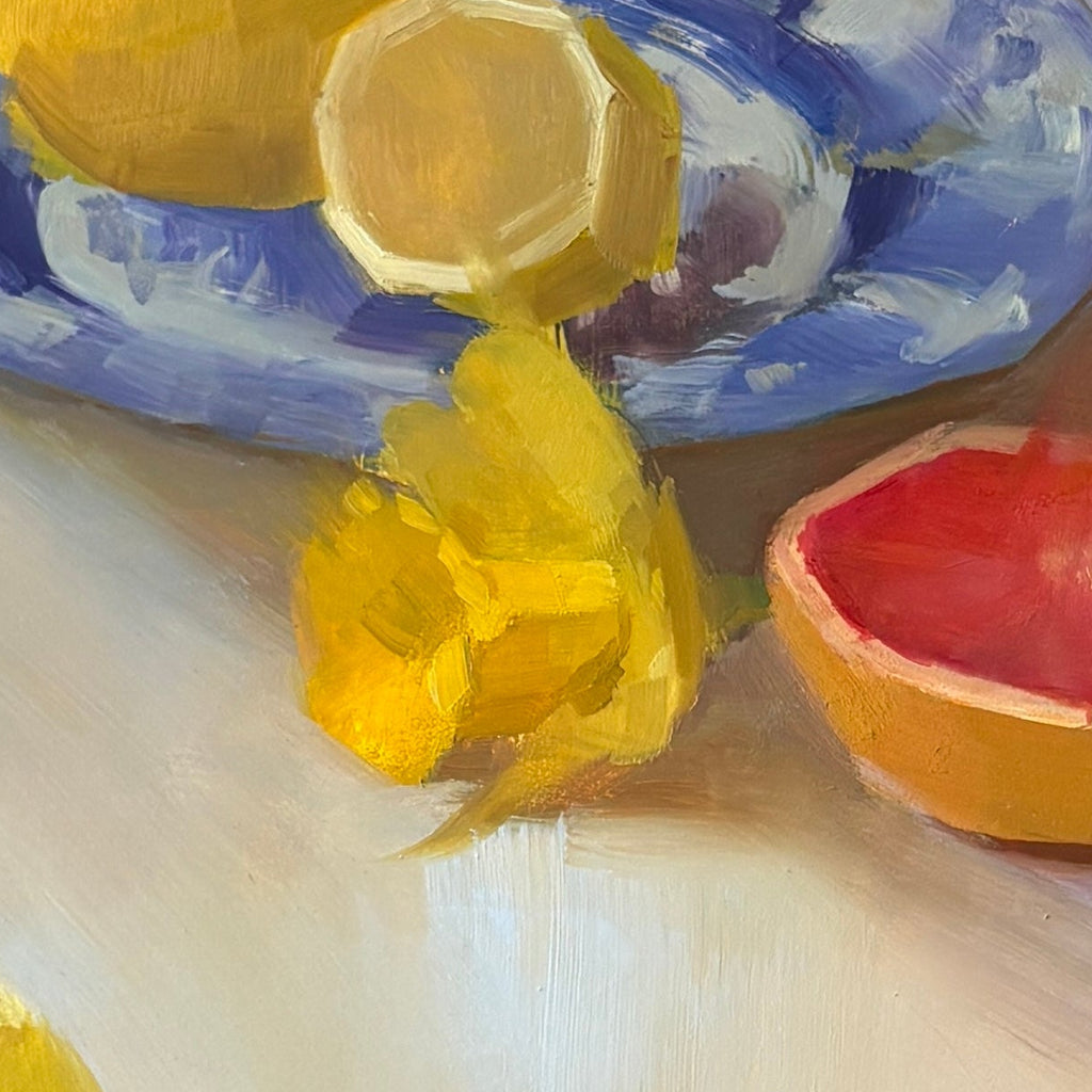 Still life with lemons, a grapefruit, and flowers on a white surface