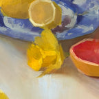 Still life with lemons, a grapefruit, and flowers on a white surface