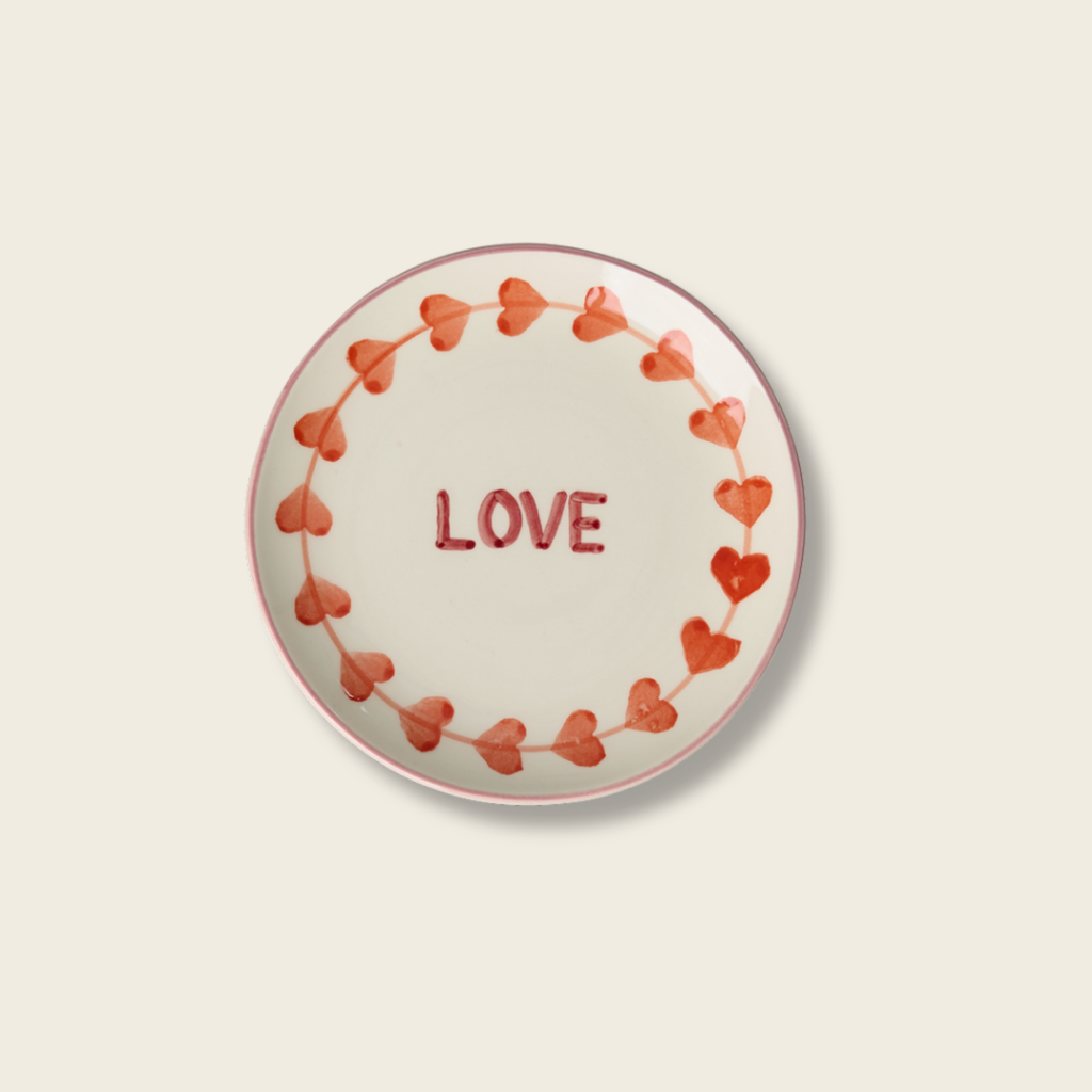 Round plate with heart designs and the word 'LOVE' on a beige background