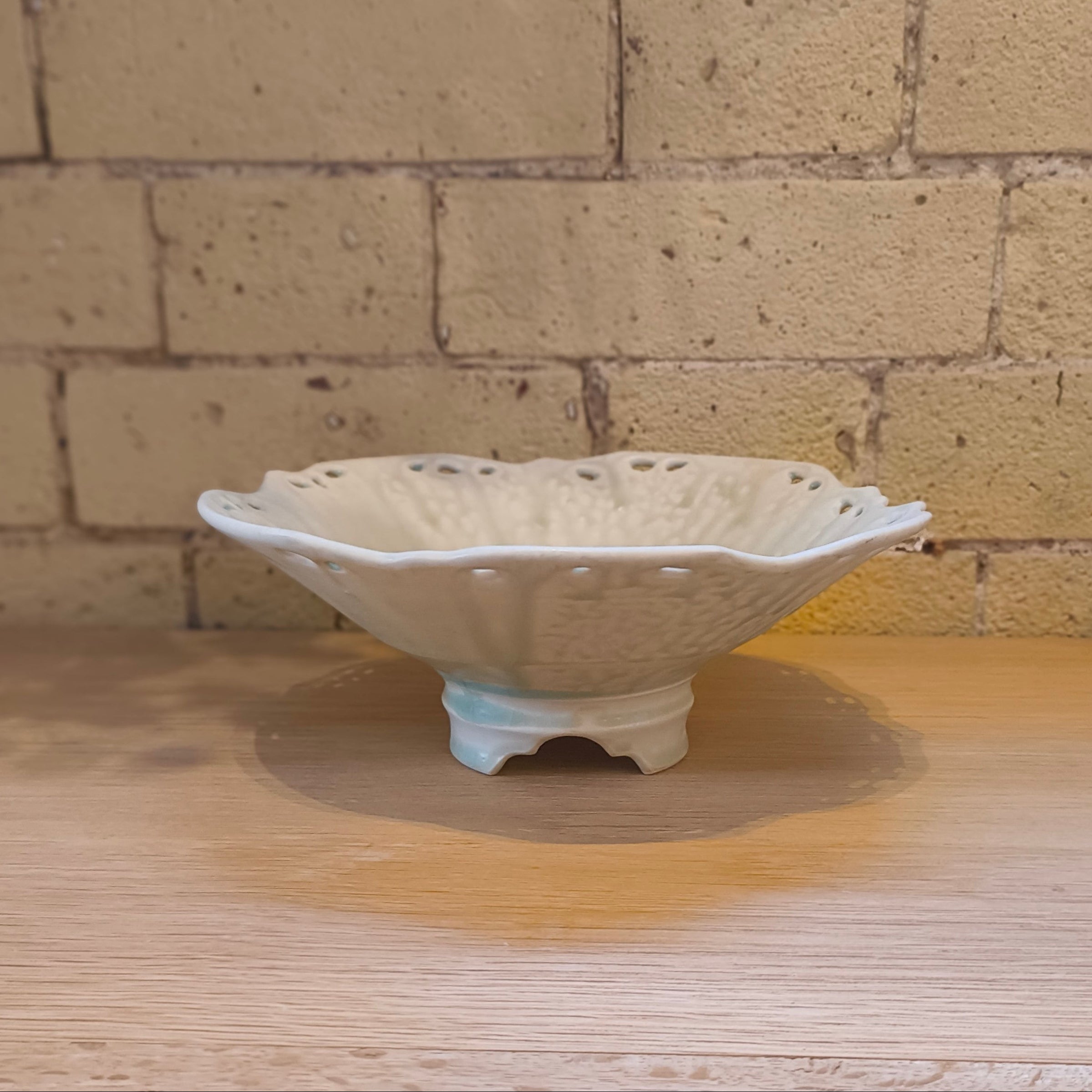 White ceramic bowl on a wooden surface with a brick wall background
