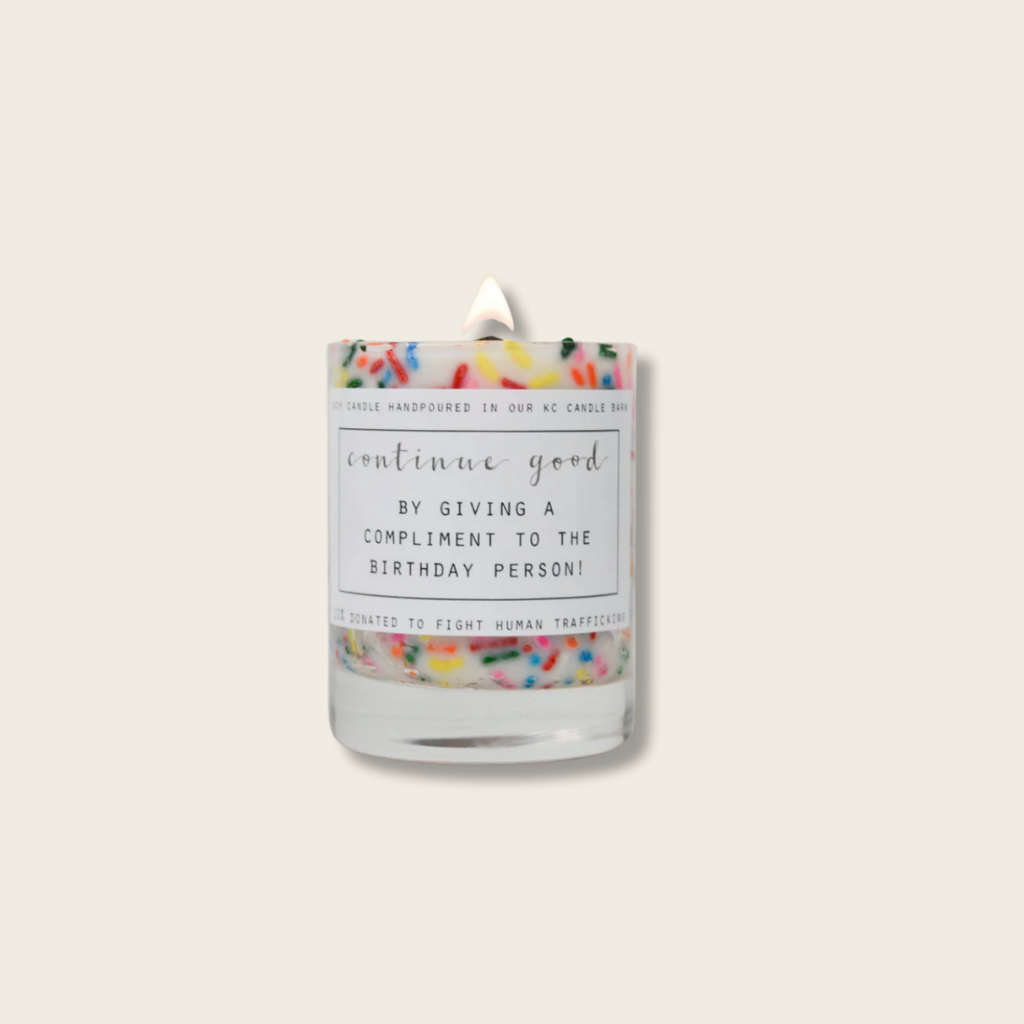 Candle with colorful label and sprinkles on a white background