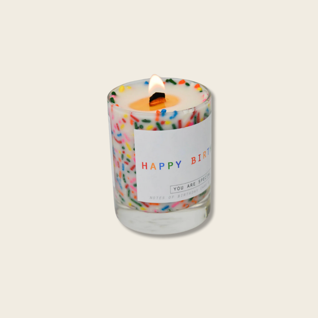 Candle with colorful sprinkles and a 'Happy Birthday' label on a light background