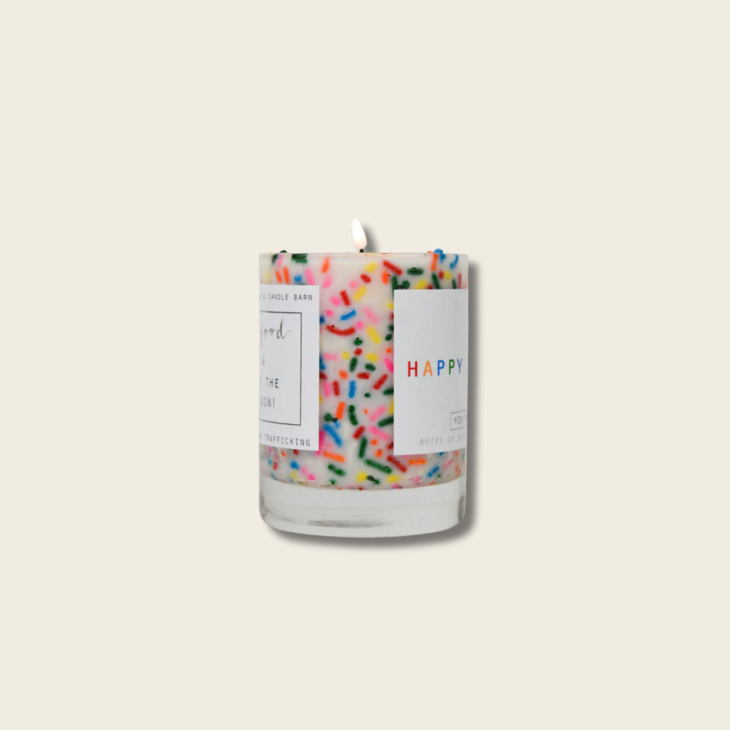 Candle with colorful sprinkles and a label on a beige background
