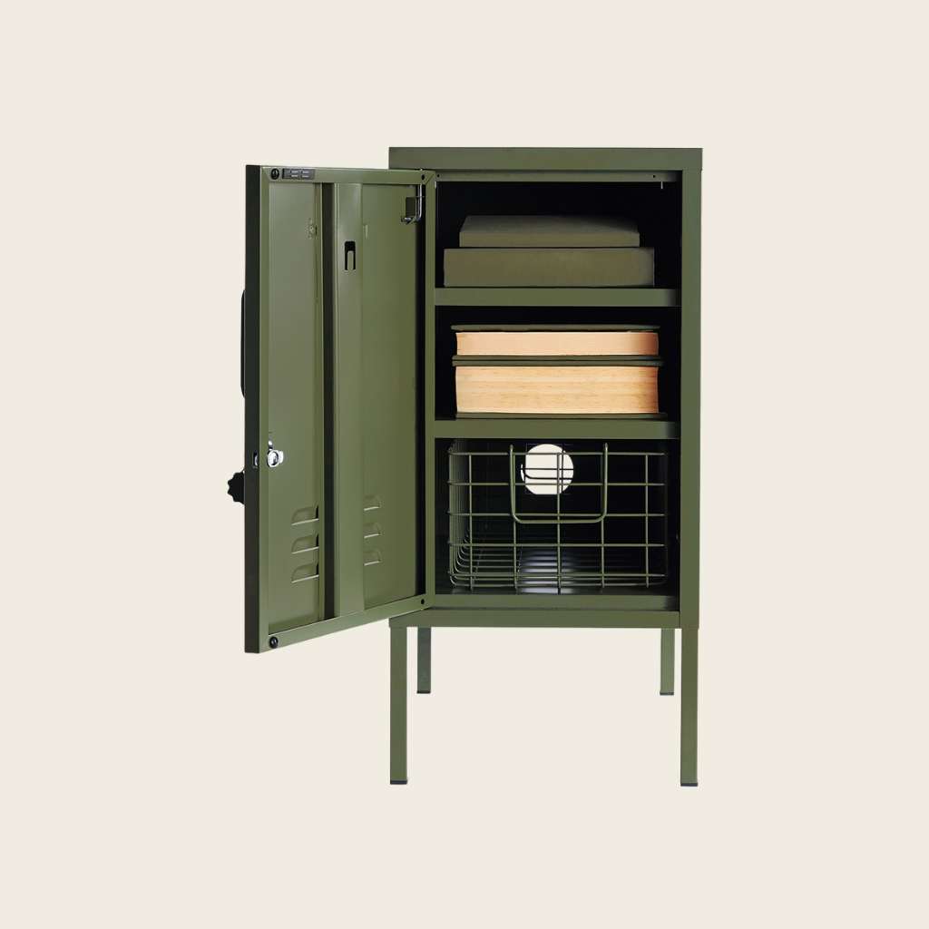Olive metal locker with door open showing books and basket on a beige background