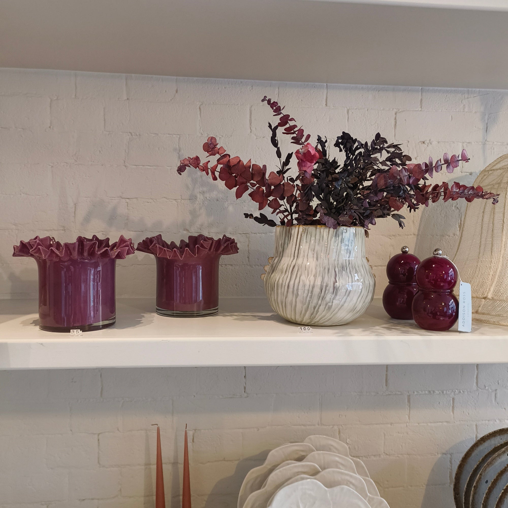 Decorative items including vases and a plant on a shelf against a tiled wall.