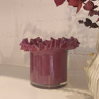 Decorative glass vase with ruffled edges and a vase on a white surface.