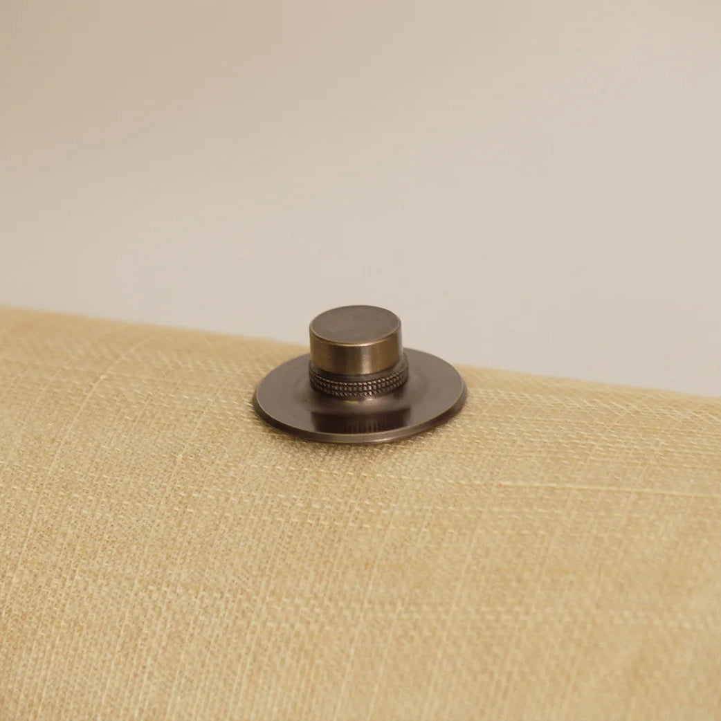 Bronze-colored metal cap on a textured beige surface with a neutral background